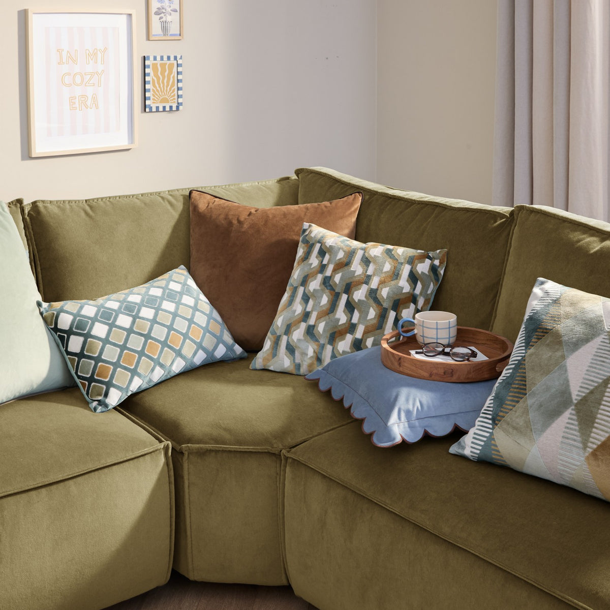 Metro Harlequin Jacquard Velvet Cushion in green on an olive velvet sofa, styled with patterned and plain cushions in a living room setting.
