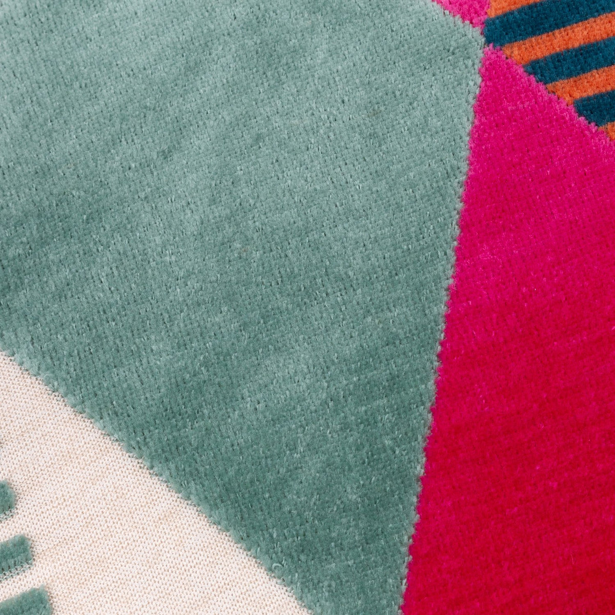 Close-up of the Metro Harlequin Jacquard Velvet Cushion, showing a geometric diamond pattern in green, pink, cream, orange and blue velvet with fine striped detailing.