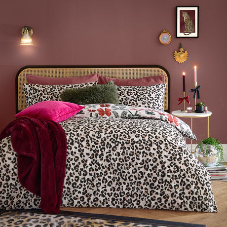 Mila Bows Reversible Duvet Cover Set in leopard print shown on a bedroom bed with matching pillowcases, dark pink cushion and burgundy throw against a mauve wall.