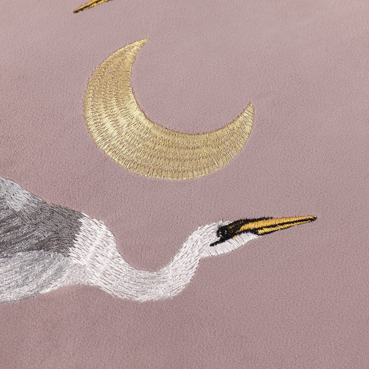 Close-up of the Moonlit Flight Animal Velvet Cushion in dusty pink, showing a gold-thread crescent moon embroidered above a grey and white stork's head and neck.