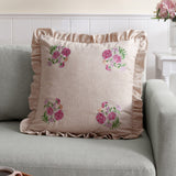 Martha Floral Linen Cushion in pink, 50x50cm with oatmeal stripe fabric, ruffled edge trim and corner floral embroidery, shown on a grey sofa.