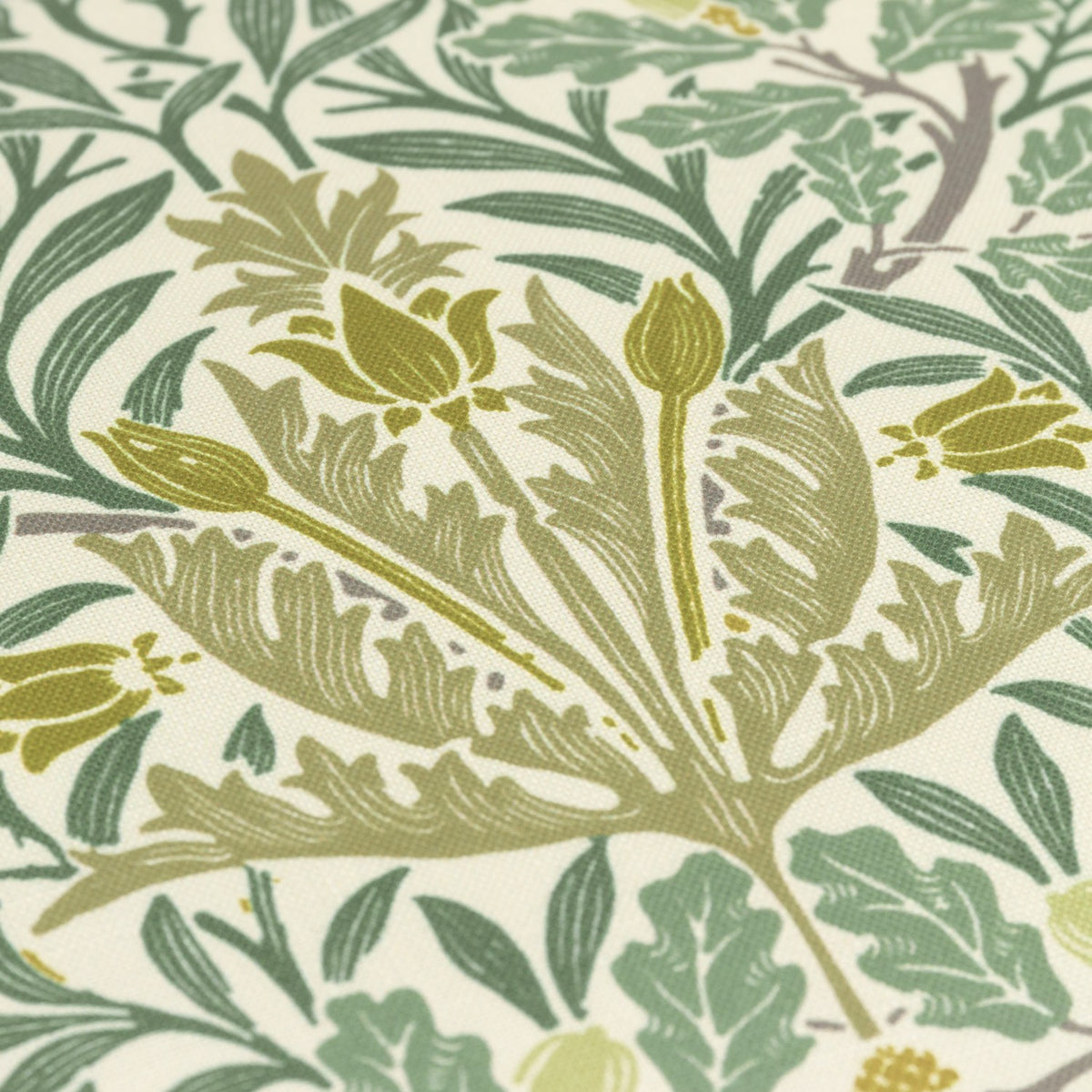 Close-up of the Multi Acorn Woodland polyester cushion fabric, showing sage and stone green leaf, branch and bud motifs printed on a cream ground.