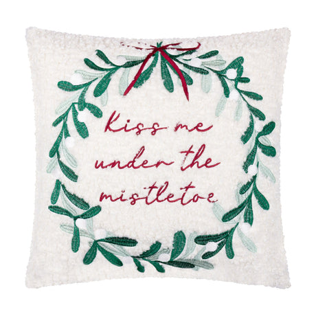 Square cream boucle cushion with an embroidered green mistletoe wreath, red ribbon and "Kiss me under the mistletoe" text, shown on a plain white background.