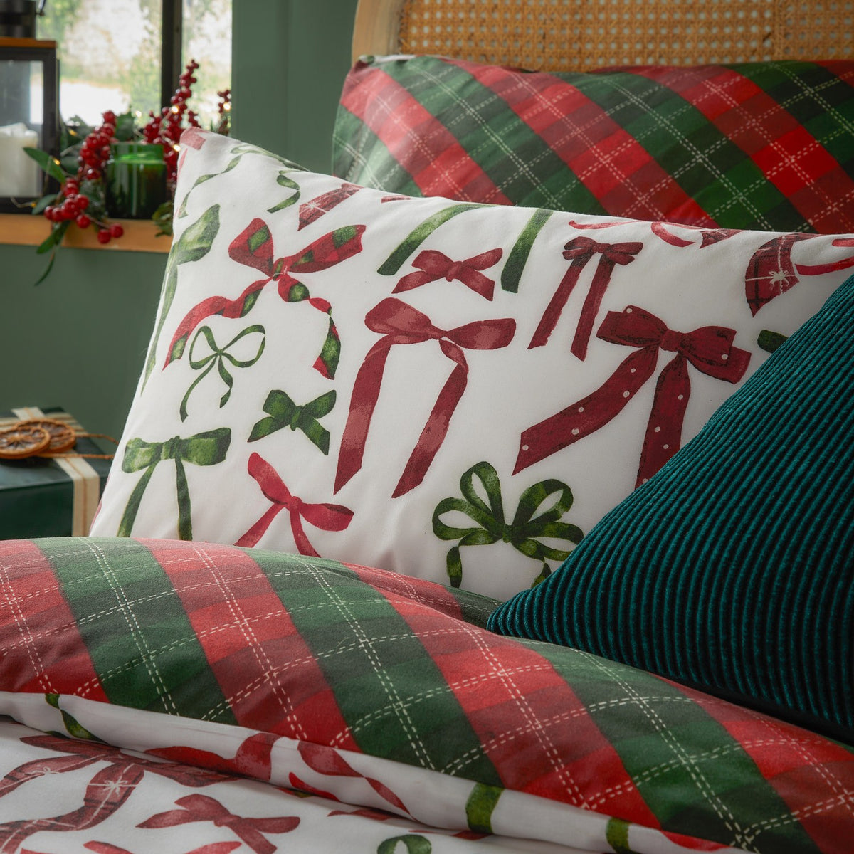 Nathalie Festive Bows Check Duvet Cover Set in Berry/Pine, showing the reversible bedding with a bow-print pillowcase and red-green tartan check duvet on a styled bed.