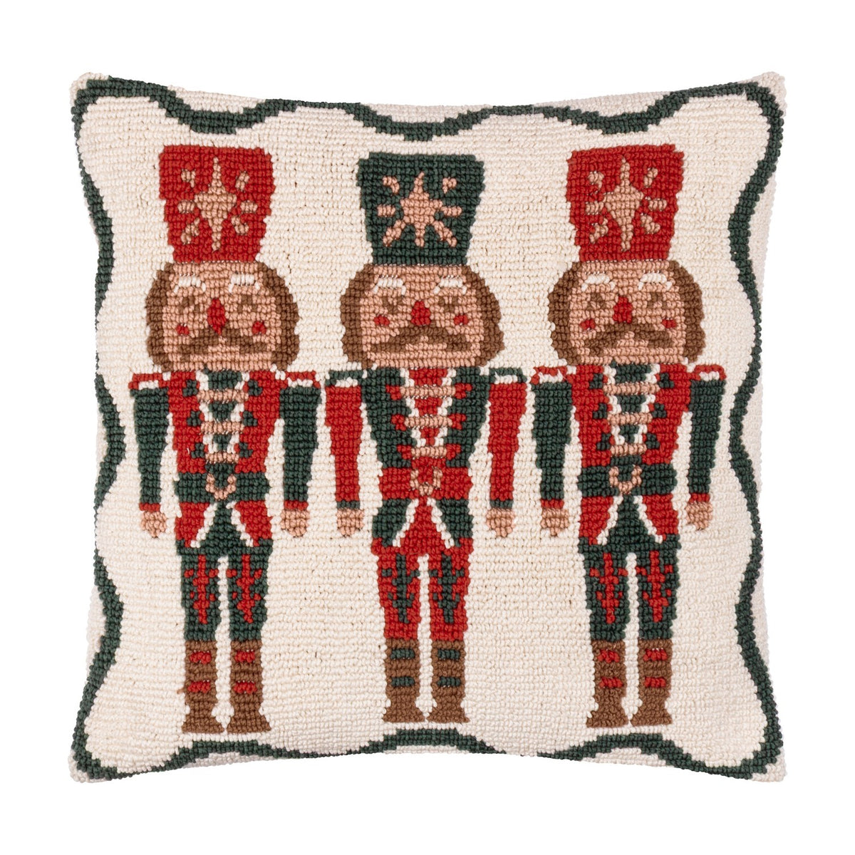 Square tufted cotton cushion featuring three red and green nutcracker soldiers on a cream ground with a scalloped green border, shown against a plain white background.