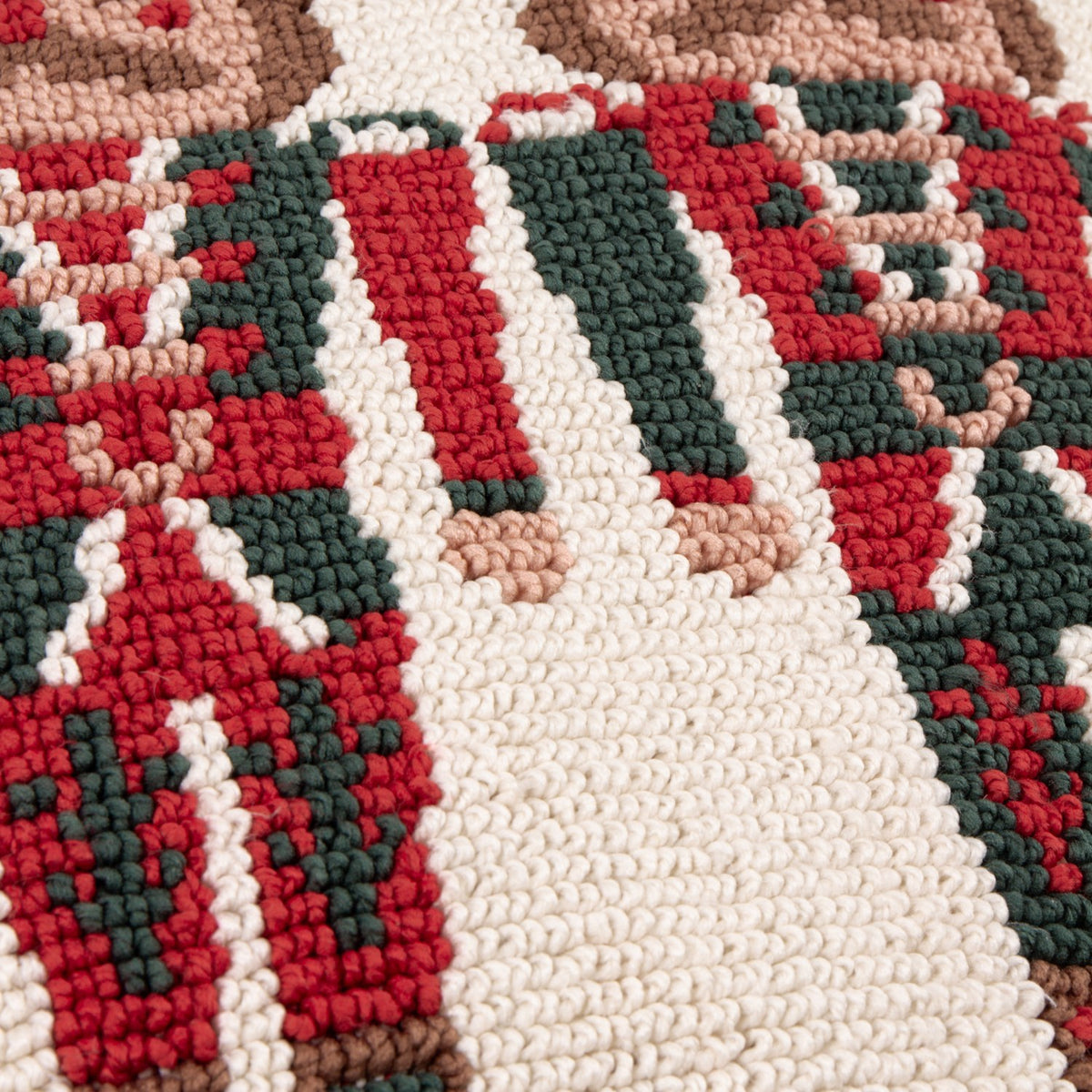 Close-up of the Nutcracker Trio Tufted Cotton Cushion, showing loop-tufted texture in red, green, cream and tan forming part of the nutcracker soldier design.