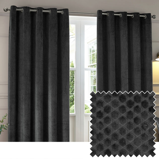 Neptune Velvet Fully Lined Eyelet Curtains in charcoal, shown as a pair on a metal pole with grommet header, styled beside a window, with a fabric swatch showing the raised honeycomb texture.