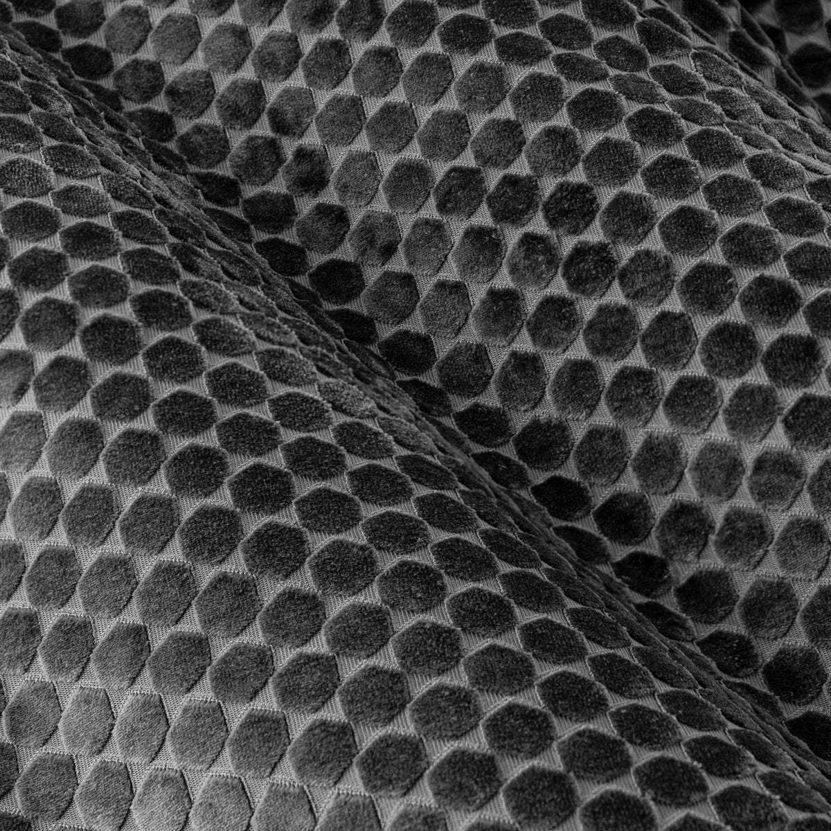 Close-up of Neptune Velvet Eyelet Curtains in charcoal, showing a raised honeycomb pattern in cut velvet with a matt-to-sheen textured finish.