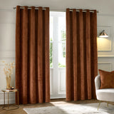 Neptune Velvet Fully Lined Eyelet Curtains in copper, hung floor-length with honeycomb-textured velvet fabric, shown framing a bright living room window.