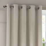 Neptune Velvet Fully Lined Eyelet Curtains in ivory with geometric honeycomb pile, shown hung on a brushed metal pole beside a window.