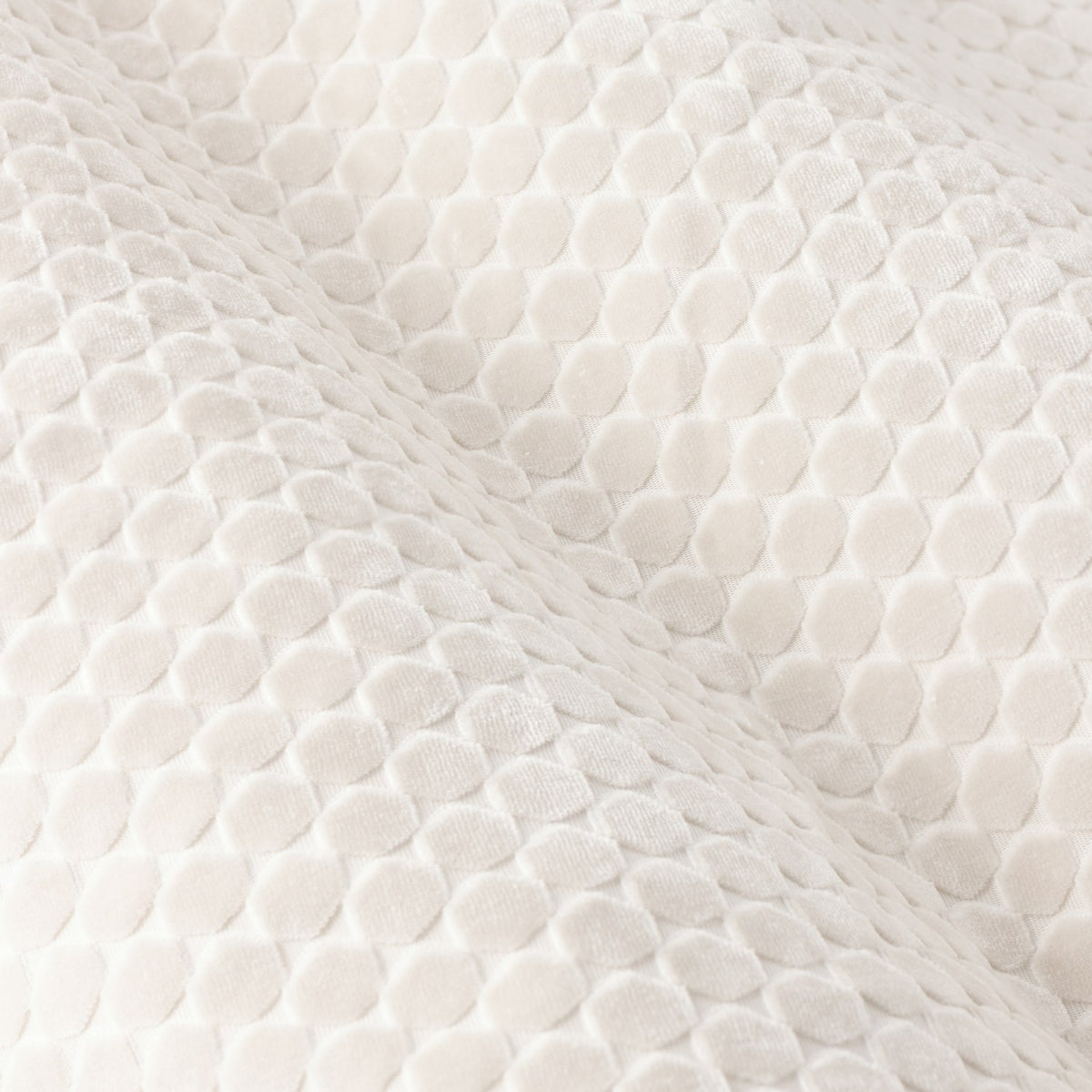 Close-up of Neptune Velvet Eyelet Curtains in ivory, showing a raised honeycomb dot pattern cut into the plush polyester velvet pile.