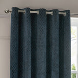 Neptune Velvet Fully Lined Eyelet Curtains in navy, showing textured cut-velvet fabric with dotted geometric pattern hung on a chrome eyelet rail beside a window.
