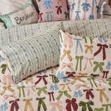 Noortje Silk Abstract Duvet Cover Set in pink with an allover bow print in green, blue, gold and red, shown with matching pillowcases and a striped leaf-pattern reverse.