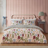 Noortje Silk Abstract Duvet Cover Set in Silk Pink, bow-print polycotton bedding with matching pillowcases on a metal bed frame in a pink-panelled bedroom.