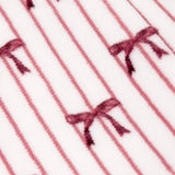 Noortje Bows Silk Throw in silk pink, close-up of fleece fabric with thin vertical stripes and scattered bow motifs in deep rose-red on a white ground.