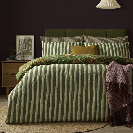 Nya Woodland Reversible Striped Duvet Cover Set in Forest green, shown striped-side up on a bed with matching pillowcases in a dark bedroom setting.
