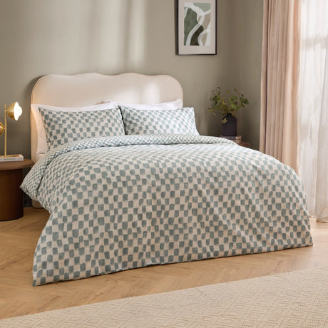 Nyhavn Reversible Check Duvet Cover Set in aqua on a bed with matching pillowcases, showing a hand-printed checkerboard pattern in a neutral bedroom setting.