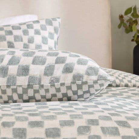 Nyhavn Reversible Check Duvet Cover Set in Aqua, shown on a bed with matching pillowcases in a hand-printed checkerboard pattern on soft white fabric.