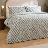 Nyhavn Reversible Check Duvet Cover Set in aqua on a bed with matching pillowcases, showing a hand-printed checkerboard pattern in a bedroom setting.