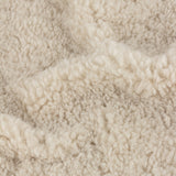 Close-up of the Olann Plain Velvet Throw in natural, showing the dense, curly shearling-look faux fleece texture on the front face.