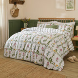 Olivia Cotton Floral Duvet Cover Set on a bed with white cotton fabric, green trellis vine print and pink, yellow and blue wildflowers, styled in a green and cream bedroom.