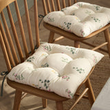 Olivia Linen Cotton Seat Pad in cream with green foliage and pink floral sprig print, tufted and tied onto wooden spindle-back dining chairs.