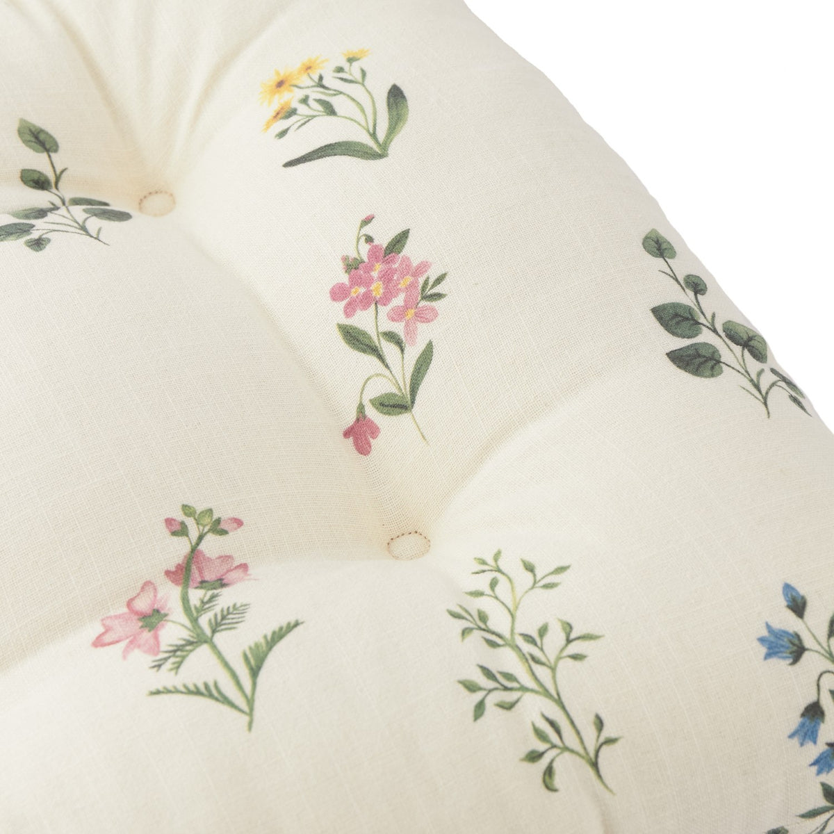 Olivia Linen Cotton Seat Pad in cream, tufted with buttons, featuring pink, yellow and blue floral sprig prints on a slub cotton weave, close-up view.