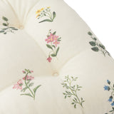 Olivia Linen Cotton Seat Pad in cream, tufted with buttons, featuring pink, yellow and blue floral sprig prints on a slub cotton weave, close-up view.