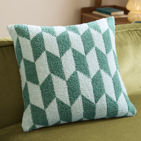 Olsen Geometric Polyester Cushion in Good For You Green, a textured knitted throw pillow with interlocking angled blocks in bottle-green and pale mint, shown on a green sofa.