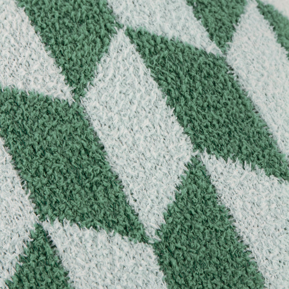 Close-up of the Olsen Geometric Polyester Cushion in Good For You Green, showing bottle-green and mint diamond blocks on a soft, knitted feather-yarn pile.