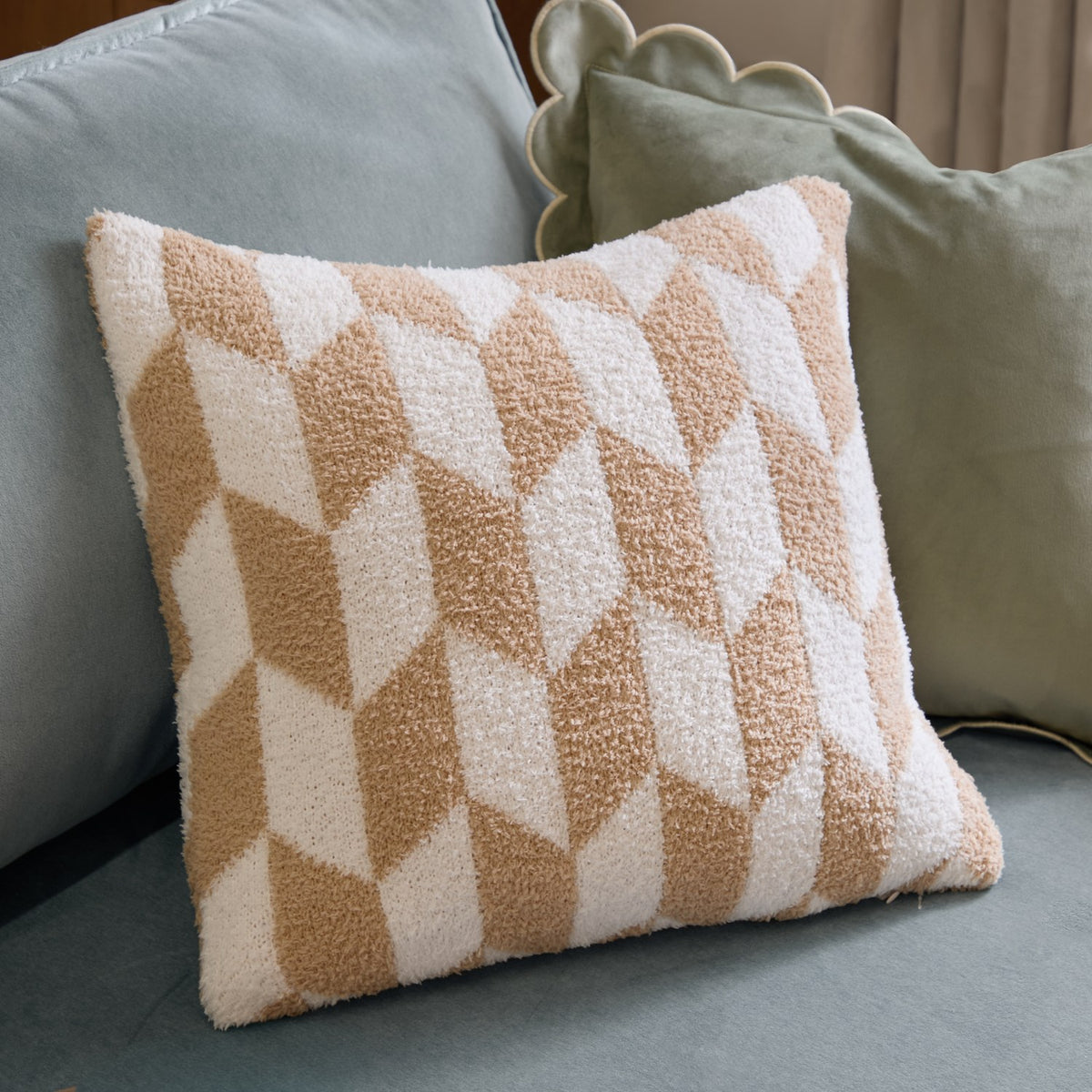 Olsen Geometric Polyester Cushion in beige and cream with a textured chevron and diamond pattern, styled on a sage green sofa.
