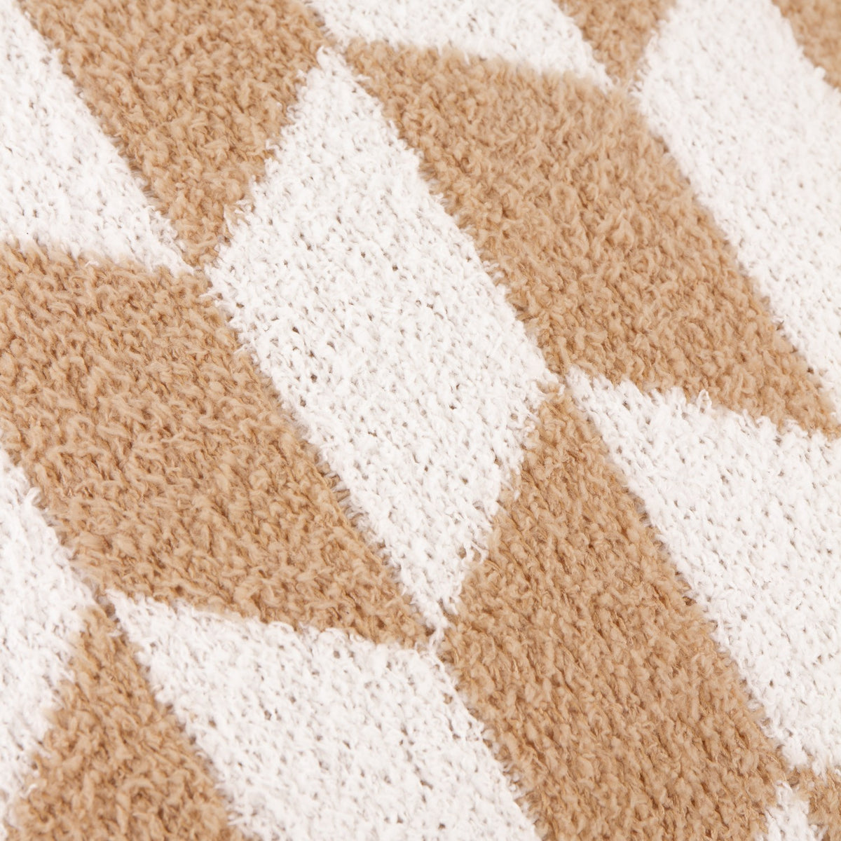 Close-up of the Olsen Geometric Polyester Cushion in beige and cream, showing a textured knitted diamond and chevron pattern on plush feather yarn fabric.