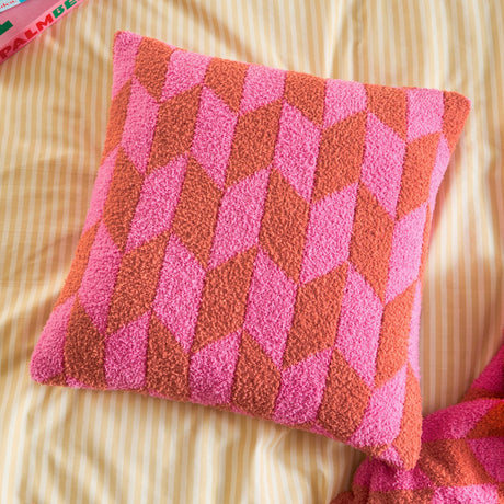 Olsen Geometric Polyester Cushion in Pink Pop, a square scatter cushion with a bold hot pink and rust chevron pattern, shown on striped bedding.
