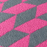 Close-up of the Olsen Geometric Polyester Cushion in Retro Pink, showing a textured knitted diamond pattern in raspberry pink and dark teal.