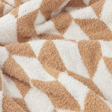 Close-up of the Olsen Geometric Polyester Throw in caramel and cream, showing its knitted feather-yarn texture and interlocking block pattern.