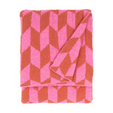 Olsen Geometric Polyester Throw in Pink Pop, folded to show a bold chevron pattern in pink and rust with a plush knitted pile, against a plain white background.