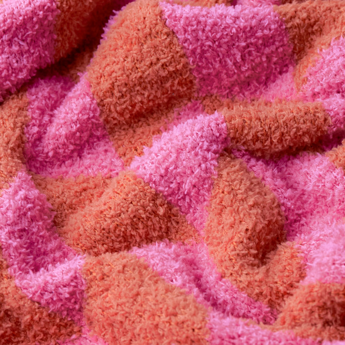 Close-up of the Olsen Geometric Polyester Throw in Pink Pop, showing a plush textured pile with a bold interlocking chevron pattern in pink and rust tones.