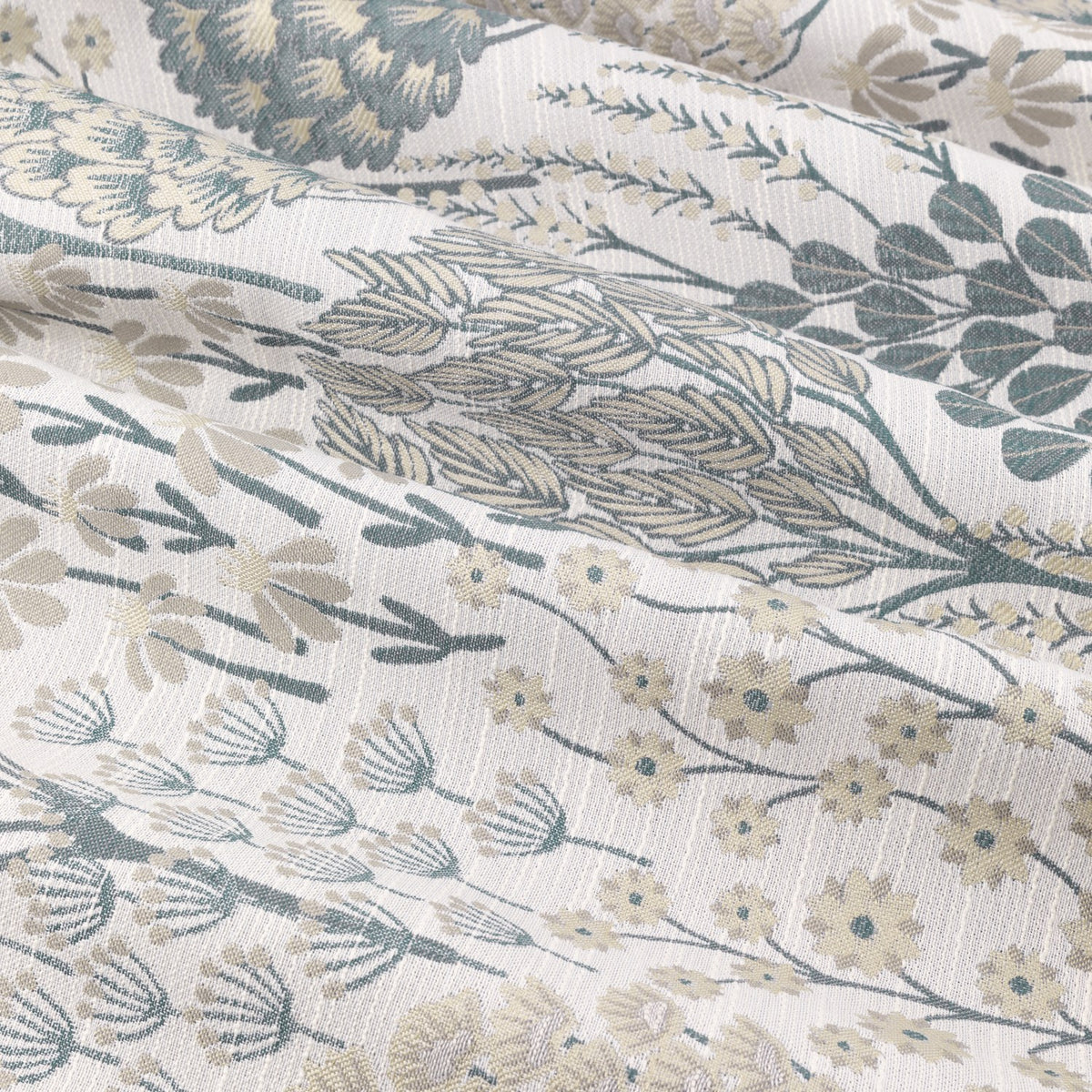 Close-up of Ophelia Jacquard Eyelet Curtains fabric in Wedgewood, showing woven floral jacquard with meadow trees, seed heads and daisy motifs in slate blue, gold and taupe on a pale ground.