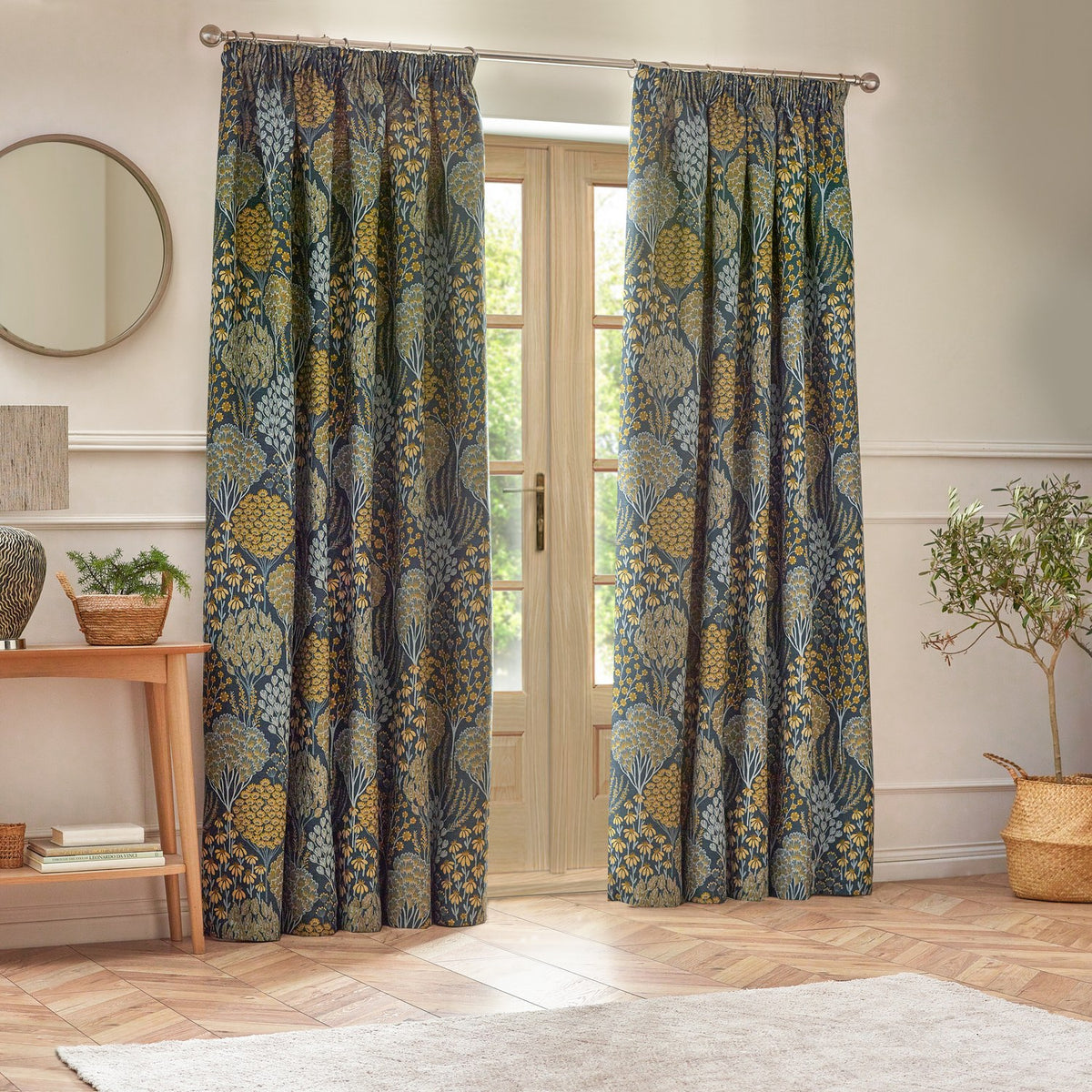Ophelia Jacquard pencil pleat curtains in blue and saffron, woven botanical pattern, hung either side of French doors in a living room.