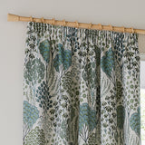 Ophelia jacquard pencil pleat curtain in Thyme/Mineral, showing botanical tree and floral pattern in green and blue-grey on cream, hung on a wooden pole with rings.