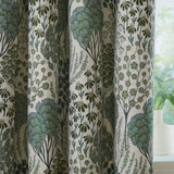 Ophelia Jacquard Pencil Pleat Curtains in Thyme/Mineral, featuring a woven botanical pattern of trees and wildflowers in green and blue-grey on cream fabric, styled by a window with a potted plant.