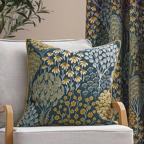 Ophelia Jacquard Polyester Cushion in blue with saffron floral pattern and gold piping, shown on a light linen armchair with matching curtain fabric visible behind.