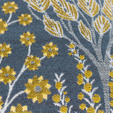 Close-up of the Ophelia Jacquard Polyester Cushion in blue, showing a woven botanical pattern with saffron flowers, seed heads and cream leaf sprays in a raised jacquard texture.