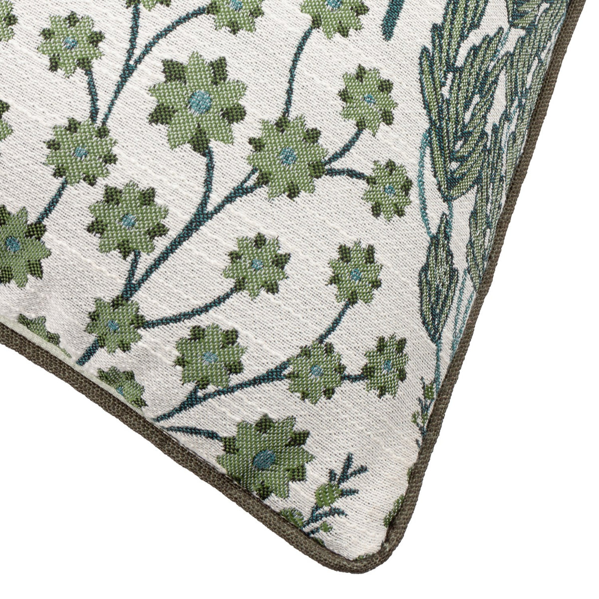Corner detail of the Ophelia Jacquard Polyester Cushion in Thyme/Mineral, showing raised star flower and branch motifs in green and blue-teal on cream with a brown piped edge.