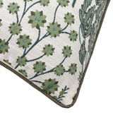 Corner detail of the Ophelia Jacquard Polyester Cushion in Thyme/Mineral, showing raised star flower and branch motifs in green and blue-teal on cream with a brown piped edge.