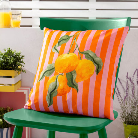 Square polyester outdoor cushion with pink and orange stripes and a watercolour orange branch design, shown on a green chair on a patio.