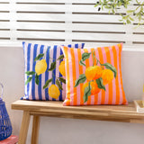 Square polyester outdoor cushion in orange and pink stripes with a watercolour orange branch design, shown beside a matching lemon-print cushion on a wooden bench.