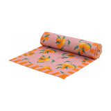 Rolled pink polyester table runner with a scattered orange fruit and leaf print, edged with an orange striped border, shown on a plain white background.