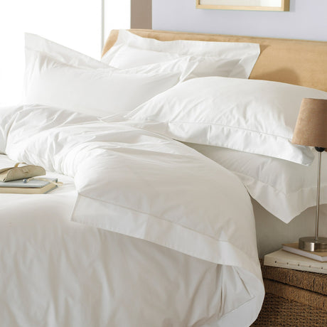White Oxford cotton duvet cover set with flat border trim, styled with matching pillowcases on a bed in a bedroom setting.