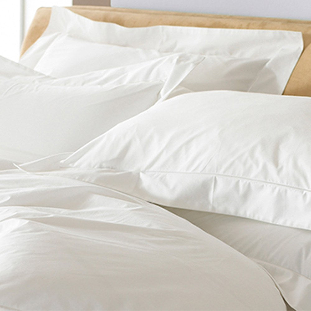 Oxford Plain Cotton Pillowcase Pair in white on a bed, showing the flat Oxford border edging and soft cotton sateen finish against white bedding.
